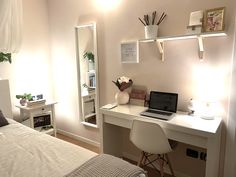 a laptop computer sitting on top of a white desk next to a mirror and lamp