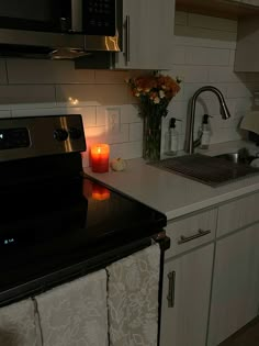 a lit candle is sitting on the counter next to a stove top oven and microwave