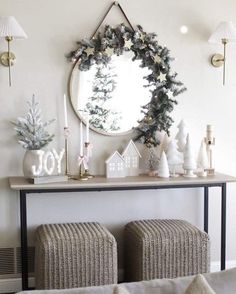 a living room with a mirror and christmas decorations on the wall next to two stools