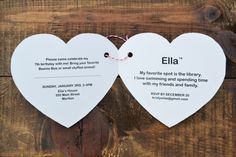 two white heart shaped paper signs with words on them hanging from a wooden wall together