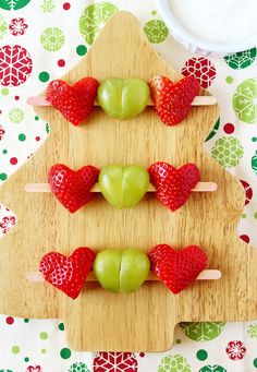 apples and strawberries are arranged in the shape of a christmas tree on a cutting board