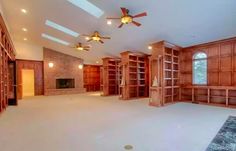 an empty living room with lots of bookshelves and ceiling fans in the corner