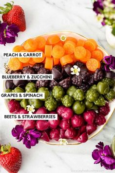 a plate filled with different fruits and vegetables on top of a white table next to purple flowers