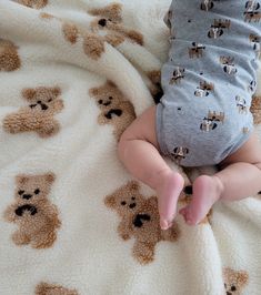 a baby laying on top of a blanket with teddy bears all over it's body