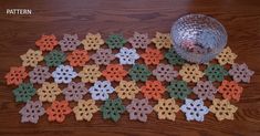 crocheted flowers on the floor next to a glass vase and bowl with water in it