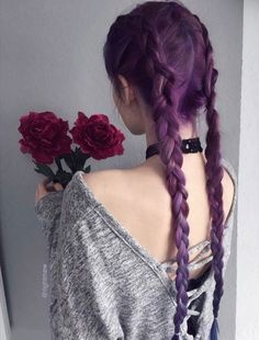 a woman with long purple hair and braids holding red roses in her left hand