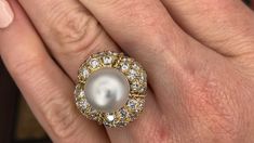 This magnificent cocktail ring is centered with one (1), post set, cultured South Sea pearl. The pearl tops a domed setting is bead set sixty-four (64), bead set, round brilliant cut diamonds. The ring has a split shank design and is accented with seven (7), bead set, round brilliant cut diamonds on each side. The ring measures 21.7mm at the top, rises 18.6mm above the finger, tapering to 2.4mm wide and 1.1mm thick at the base of the shank. The ring is currently size 7. Elegant White Domed Rings, Elegant White Domed Jewelry, Elegant Cabochon Rings For Anniversary, Classic Cabochon Pearl Ring For Formal Occasions, Classic Formal Pearl Ring With Cabochon, Luxury Akoya Pearl Jewelry For Party, Luxury Akoya Pearl Party Jewelry, Luxury Oval Pearl Ring, Luxury Pearl Drop Ring For Formal Occasions