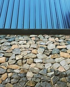 a cat is sitting on top of a pile of rocks next to a blue building