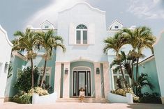 a person standing in front of a large blue building with palm trees on both sides