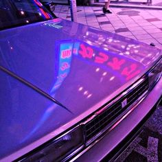 a car parked on the side of the road with a neon sign on it's hood