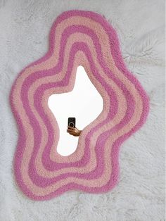 a pink and white rug with a mirror in the middle