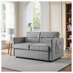 a gray couch sitting on top of a rug in a living room next to a window