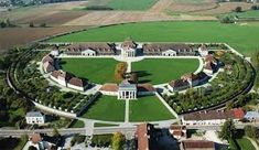 an aerial view of a large building surrounded by green fields