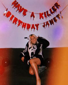 a woman sitting on top of a couch in front of a birthday banner