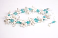 a white necklace with blue beads and pearls