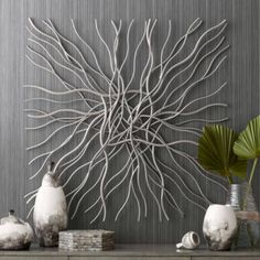 some white vases sitting on top of a wooden table next to a wall sculpture