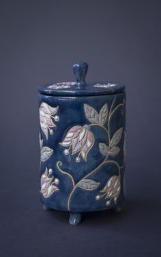 a blue vase with flowers painted on the outside and inside, sitting on a black surface