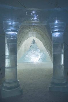 the inside of an ice hotel with snow on the ground and columns in front of it