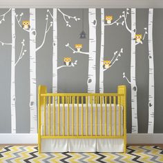 a baby's room with yellow crib and wall decals