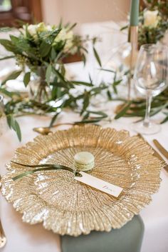 the table is set with gold plates and place settings