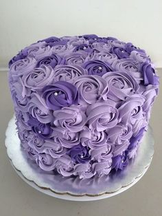 a cake with purple frosting and flowers on top is sitting on a white plate