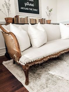 a white couch sitting on top of a rug next to a wooden table and chair