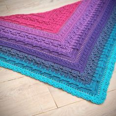 a crocheted blanket is laying on the floor with it's edges folded down