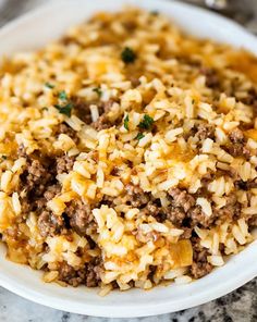 a white bowl filled with rice and ground beef on top of a marble countertop