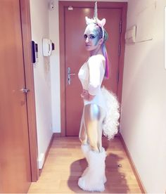 a woman dressed as a unicorn standing in a hallway