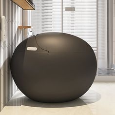 a large black ball sitting in the middle of a room next to a window with blinds