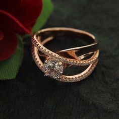 two gold rings with diamonds on them next to a red rose