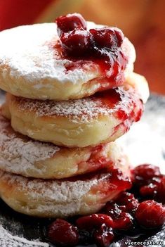 a stack of cranberry filled donuts sitting on top of a plate covered in powdered sugar