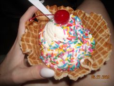 a person holding a waffle with ice cream and sprinkles