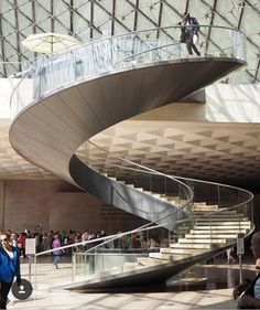 people are walking up and down the stairs in a building with a glass dome ceiling