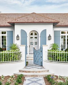 a white house with blue shutters on the front door and steps leading up to it