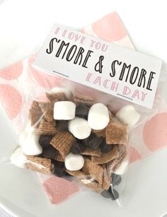 a bag filled with marshmallows and s'mores on top of a white plate