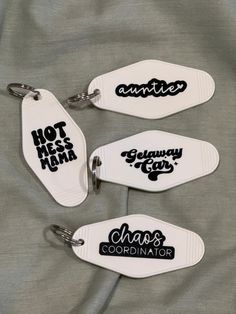 three white key chains with black lettering on them