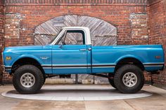 a blue truck parked in front of a brick wall