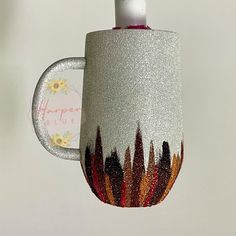 a coffee cup with flowers painted on the side and inside is hanging from a hook