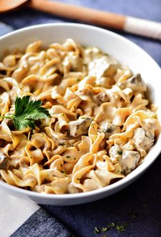 a white bowl filled with pasta and meat on top of a checkered table cloth