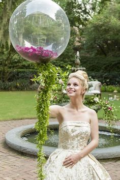 a woman in a white dress is holding a large bubble ball and smiling at the camera