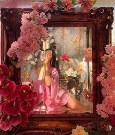 a woman sitting in front of a mirror surrounded by flowers