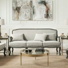 a living room with two couches, coffee table and paintings on the wall behind them