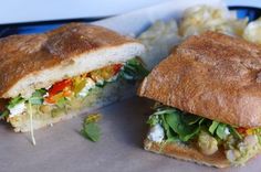 a sandwich cut in half sitting on top of a blue plate next to potato chips