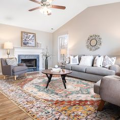 a living room filled with furniture and a fire place under a ceiling fan on top of a wooden floor