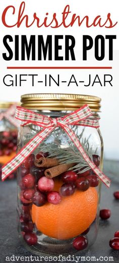 a glass jar filled with oranges and cranberries on top of a table