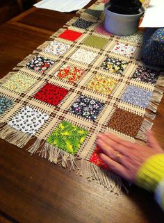 someone is working on a patchwork table runner made out of squares and fringes