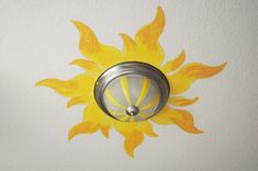 a yellow flower painted on the wall next to a light