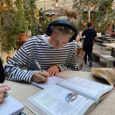 two women sitting at a table with notebooks and headphones