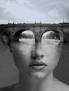 a woman's face is reflected in the water next to a bridge that crosses over a body of water